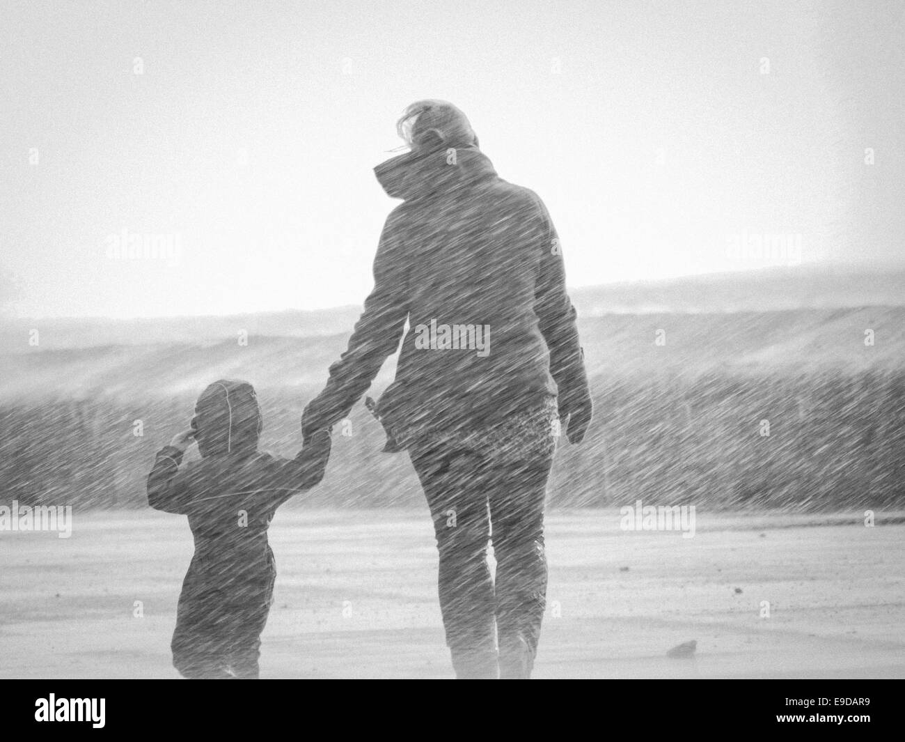 Una madre e un bambino a piedi sul lungomare sono catturati da una rottura d'onda oltre la parete del mare Foto Stock