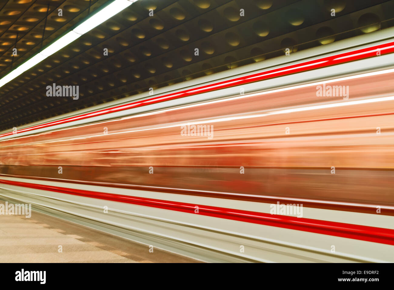 Rapido sentiero sfocata del treno in movimento del traffico in pubblico illuminato dalla stazione della metropolitana Foto Stock