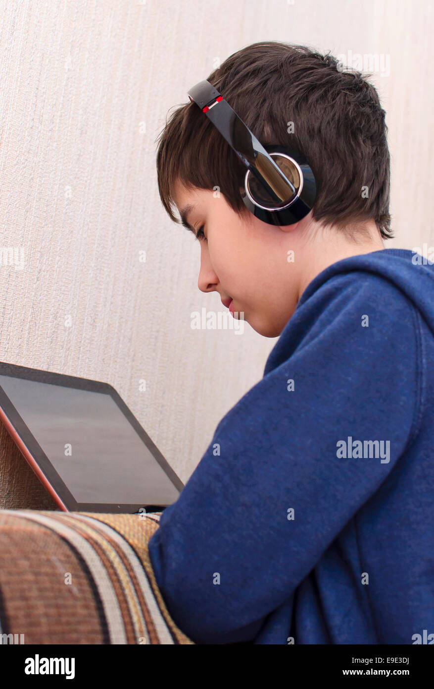 Boy utilizzando le cuffie e il suo tablet, gadget, la dipendenza da Internet Foto Stock
