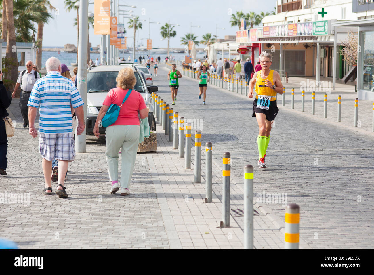 Si tratta di una la domenica mattina. La gente camminare lungo la passeggiata a mare e alcune persone corrono 10k città di Paphos Run (Afrodite mezza maratona). Foto Stock