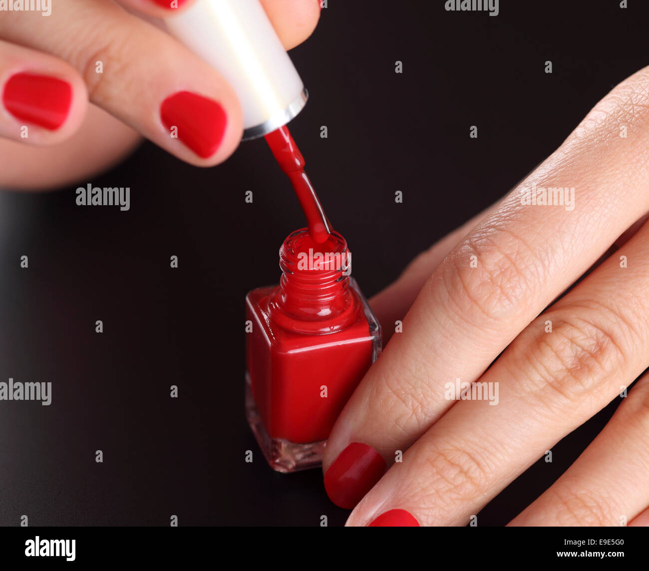 Aprire la bottiglia di rosso di smalto per unghie in donna curati palms su sfondo nero. Foto Stock