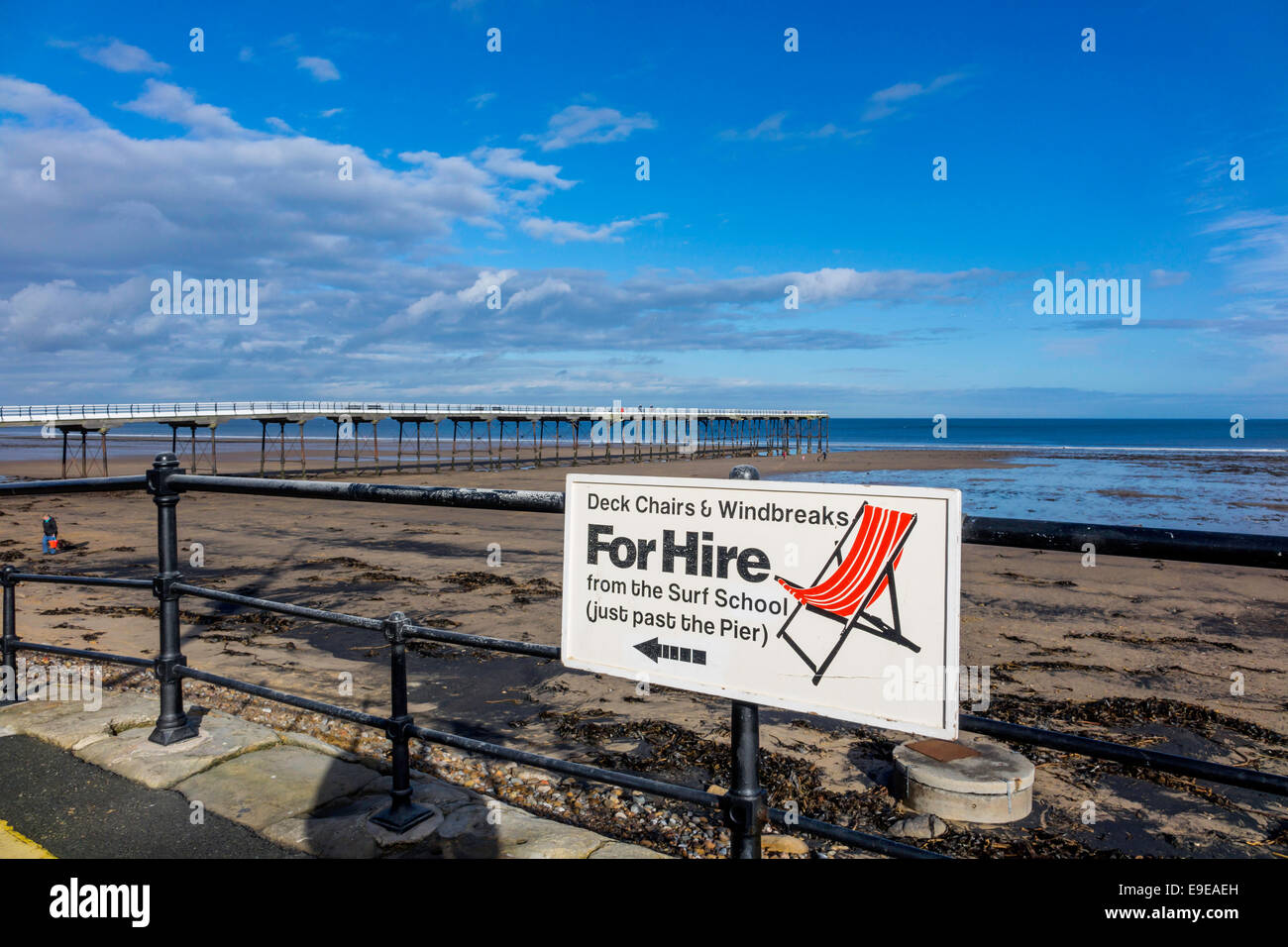 Saltburn Pier su un caldo e soleggiato autunno il giorno spiaggia vuota e firmare per il noleggio di sedie a sdraio e frangivento Foto Stock