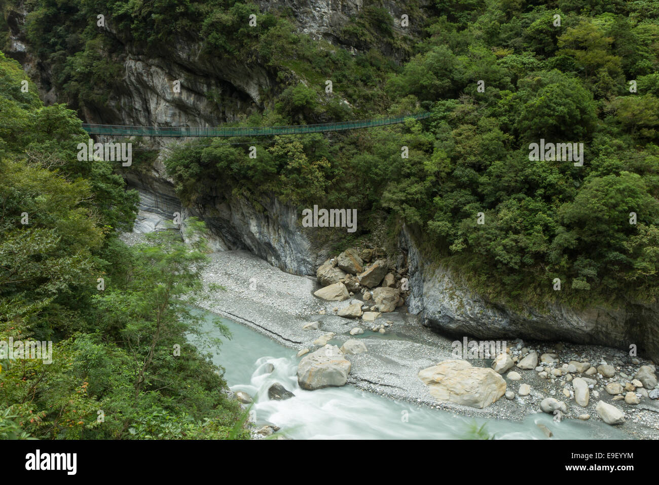 Lussureggiante foresta, ripida scogliera e sospensione ponte su un fiume roccioso a Taroko National Park di Taiwan Foto Stock