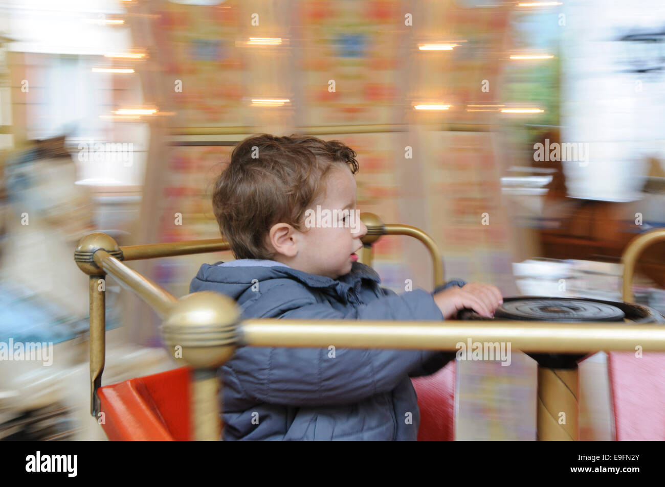 Un giovane bambino su un Merry Go Round con effetto di panning. Modello rilasciato Foto Stock