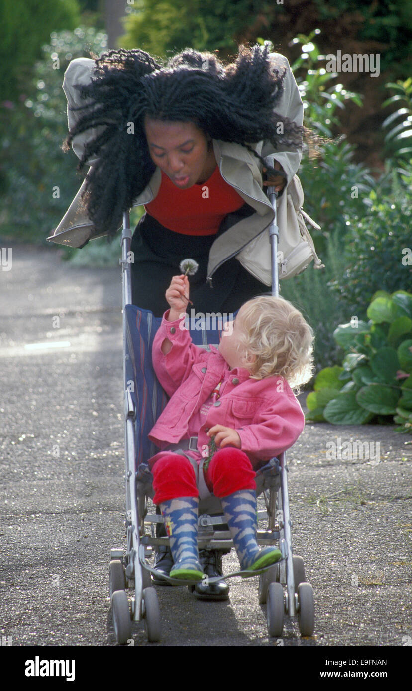 Childminder spingendo bambina in buggy Foto Stock