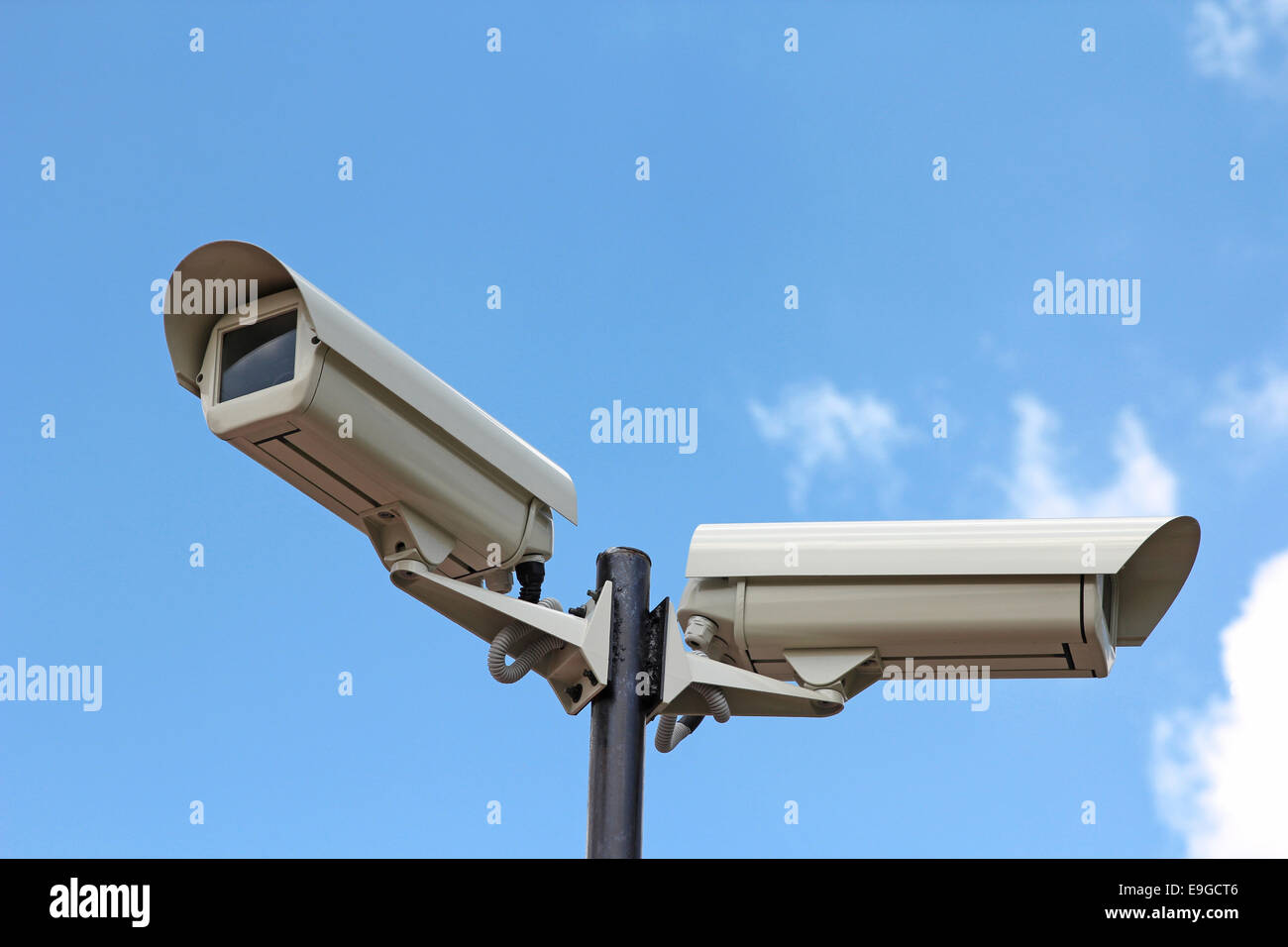 Due videocamere di sicurezza contro il cielo blu Foto Stock