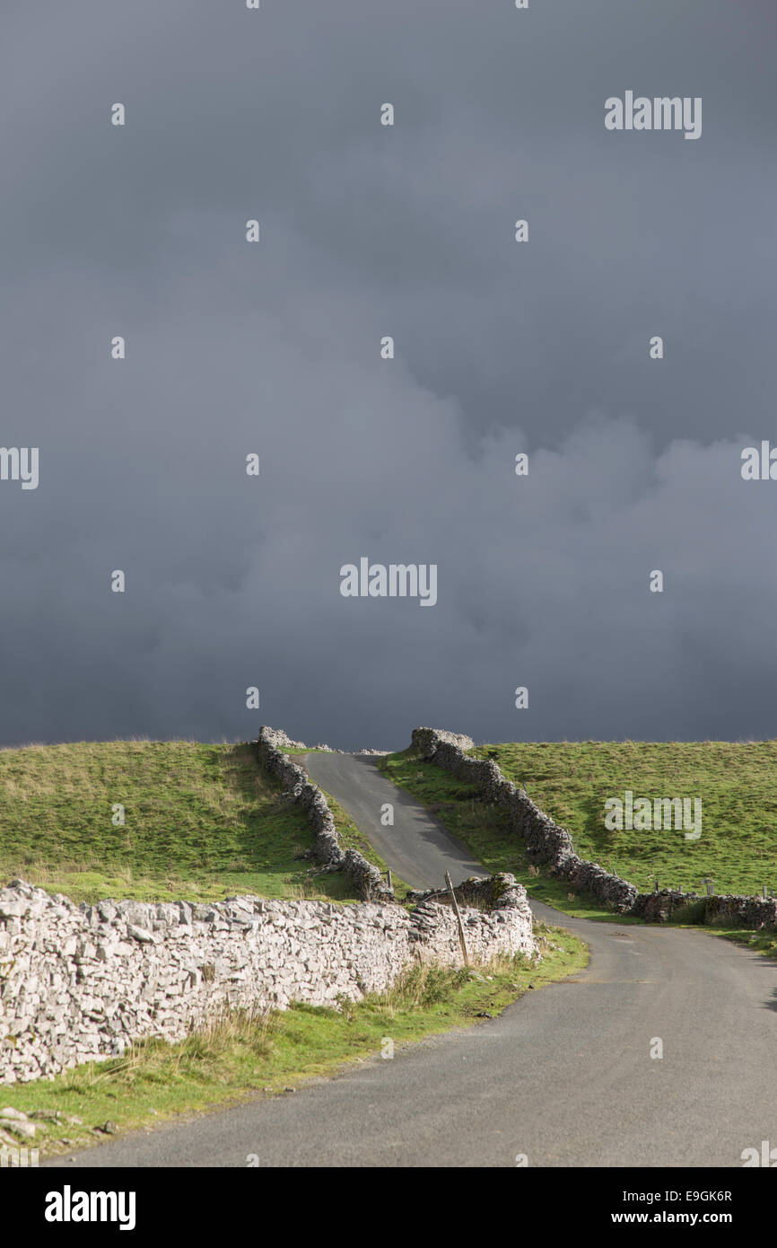Nuvole temporalesche su un dales country lane, Yorkshire Dales National Park, North Yorkshire, Inghilterra, Regno Unito Foto Stock