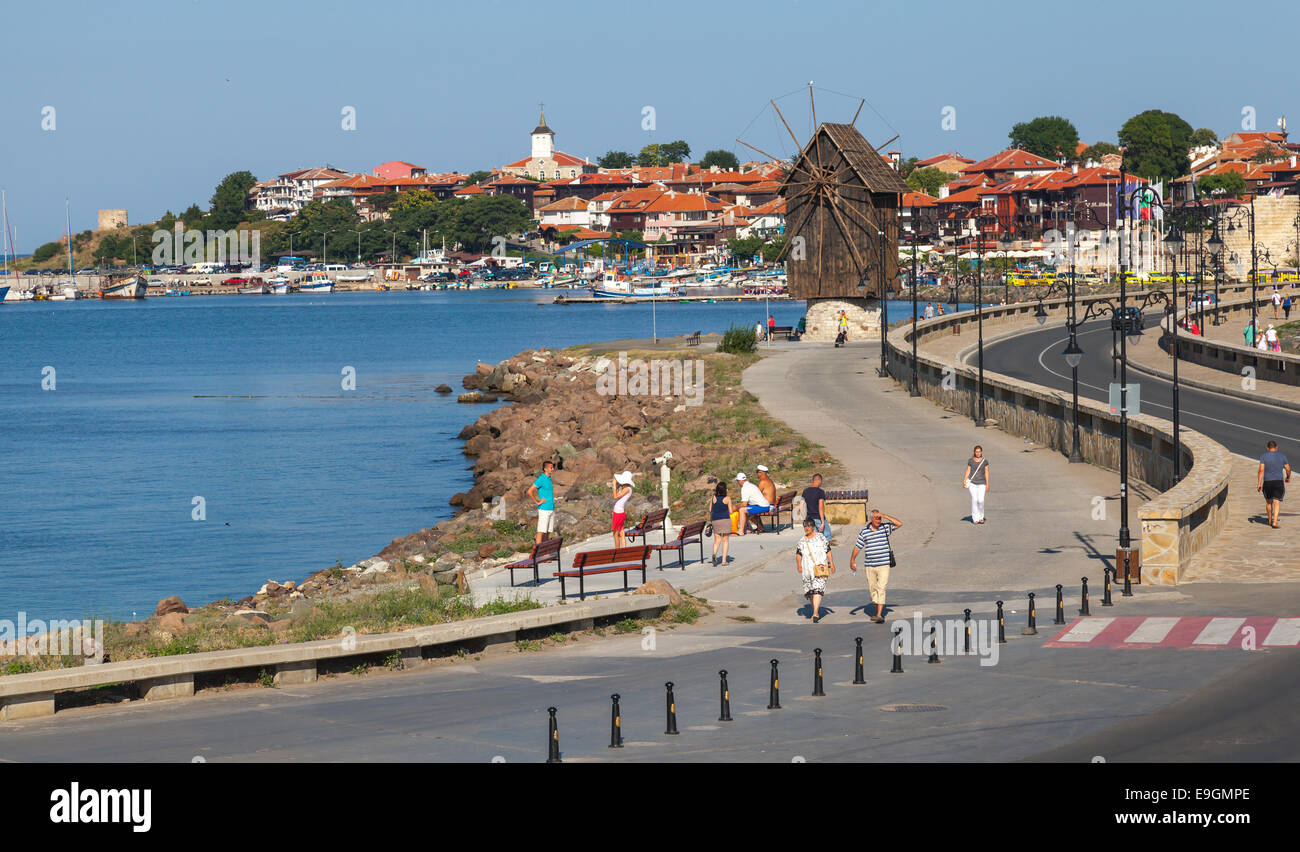 Nesebar, Bulgaria - 21 Luglio 2014: il paesaggio costiero con il trasporto su strada e il vecchio mulino a vento, il litorale del Mar Nero in giornata soleggiata. I turisti a piedi su Foto Stock