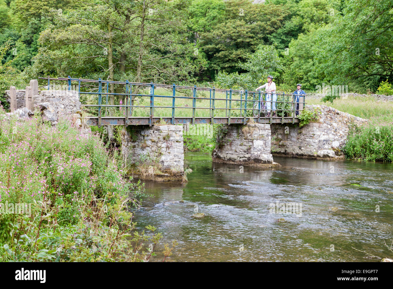 Le persone che attraversano il ponte sopra il fiume Wye a Upperdale nel Derbyshire Dales, Parco Nazionale di Peak District, England, Regno Unito Foto Stock