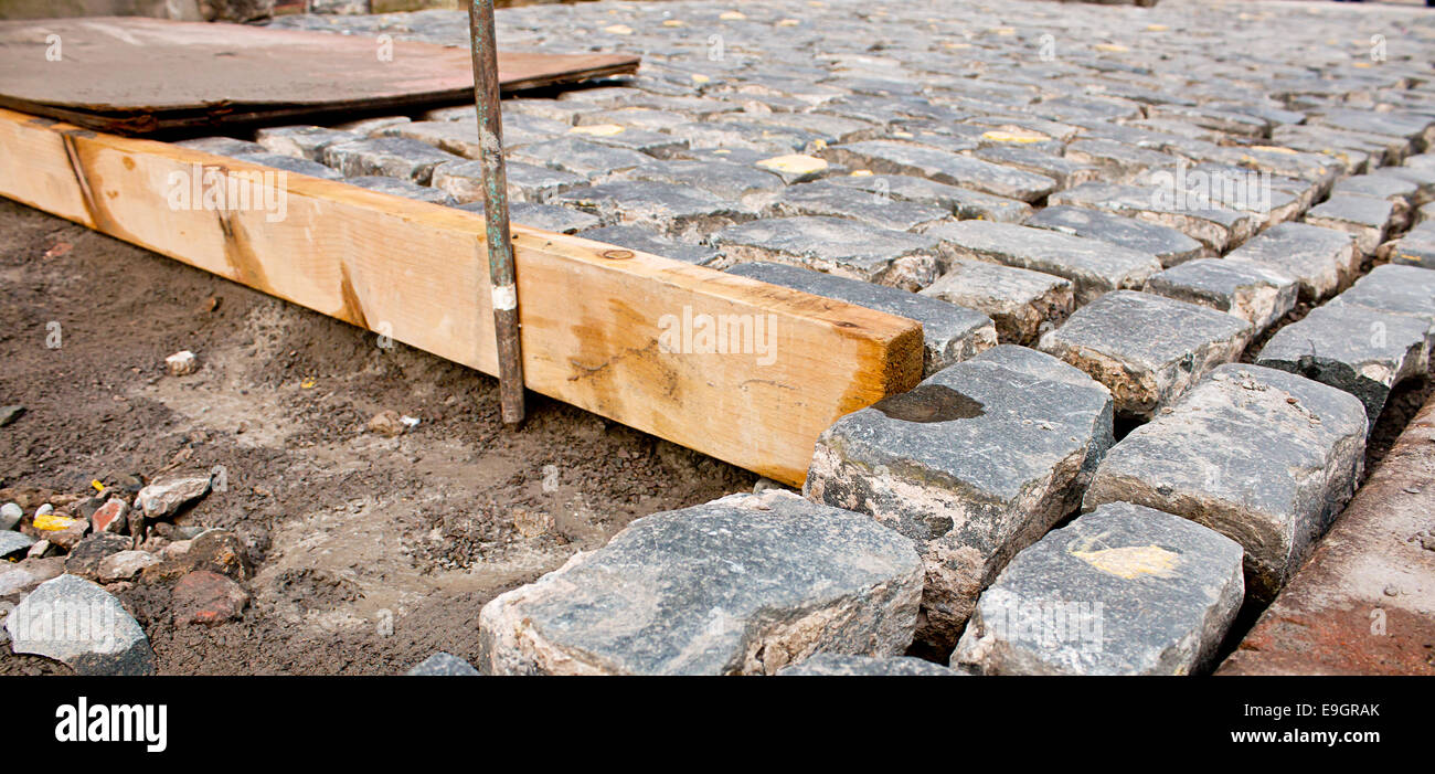 Ciottoli tradizionale pavimentazione in pietra essendo posizionate dal contattore di costruzione Foto Stock