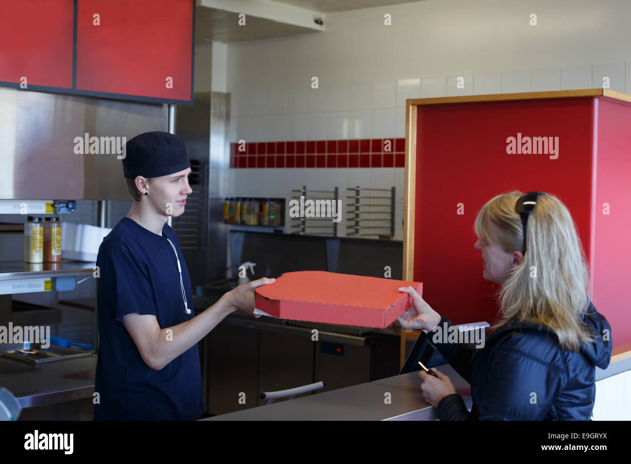 Ragazzo consegnare la pizza in un ristorante fast food Foto Stock