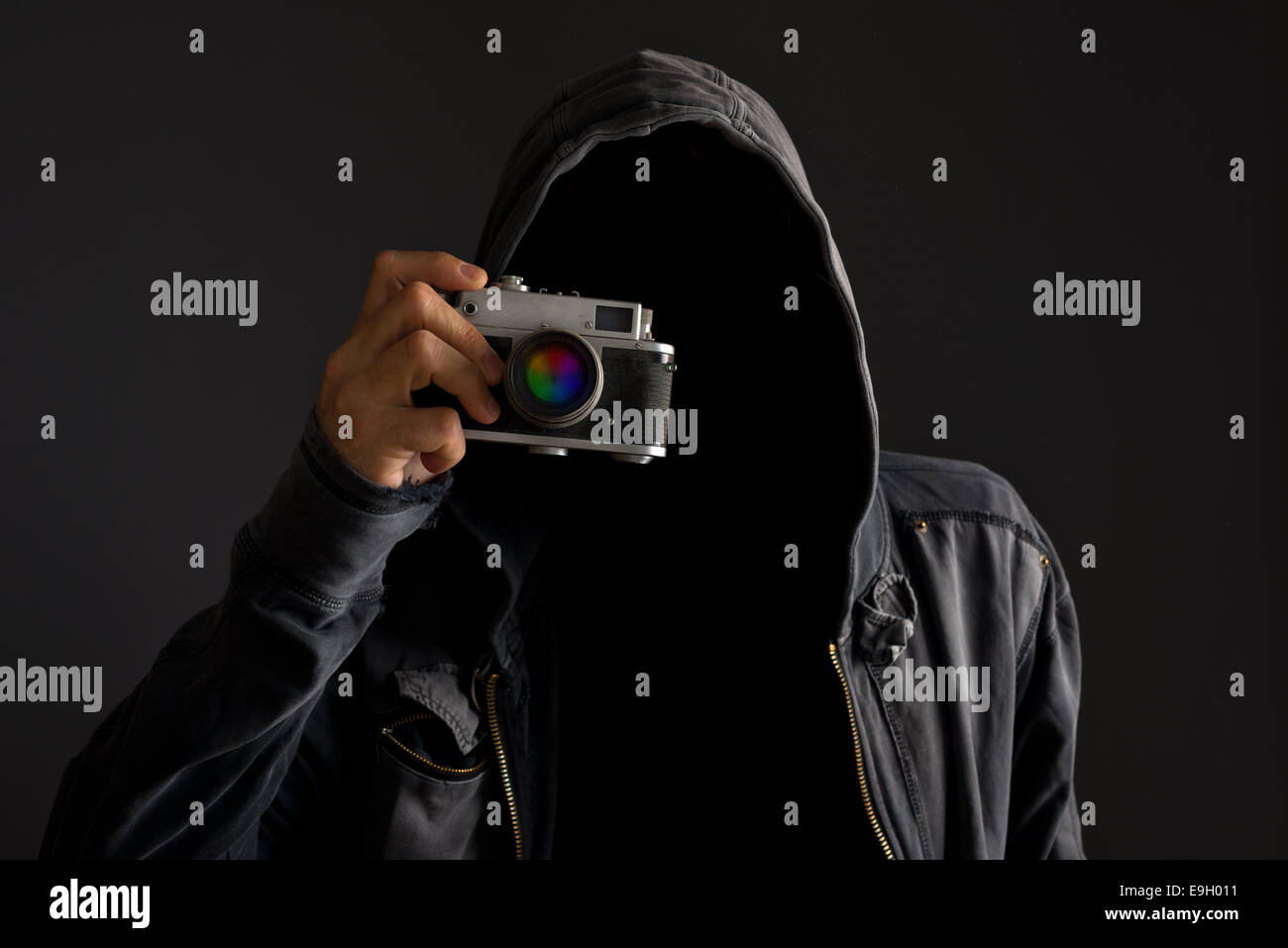 L'uomo senza volto con hoodie jacket holding polveroso film vintage fotocamera e scattare fotografie. Foto Stock