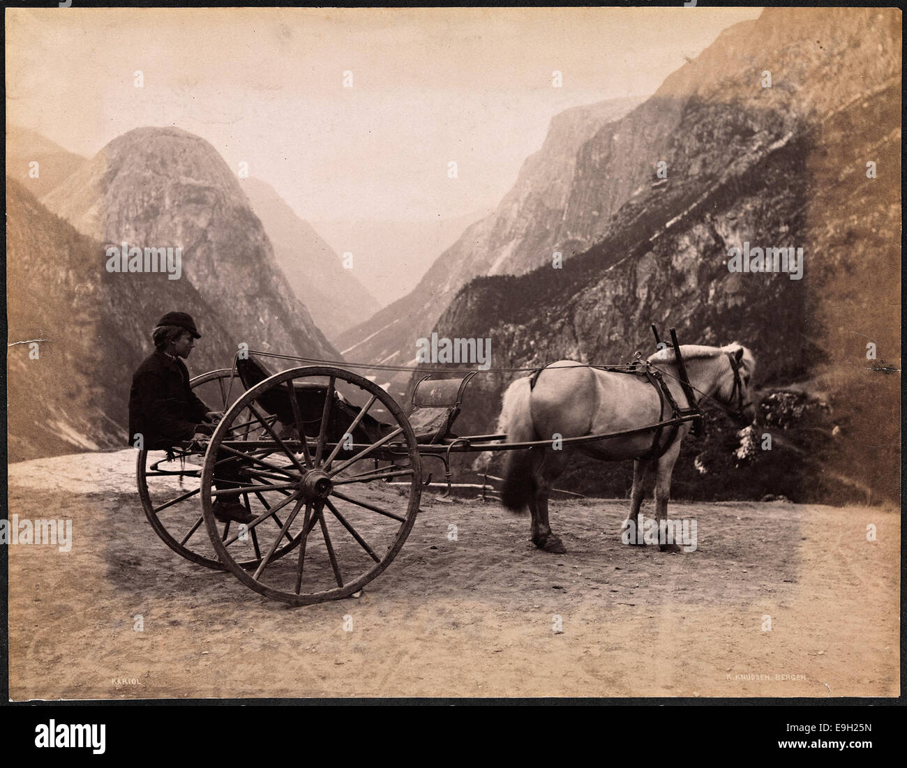 Questa fotografia storica mostra i ragazzi che cavalcano su un kariol (un tipo di carro a due ruote) trainati da cavalli, adagiati su un paesaggio rurale. L'immagine è stata scattata in Norvegia e fa parte della collezione della Biblioteca Nazionale di Norvegia, evidenziando i metodi di trasporto tradizionali e le attività infantili dei primi anni del XX secolo. Foto Stock