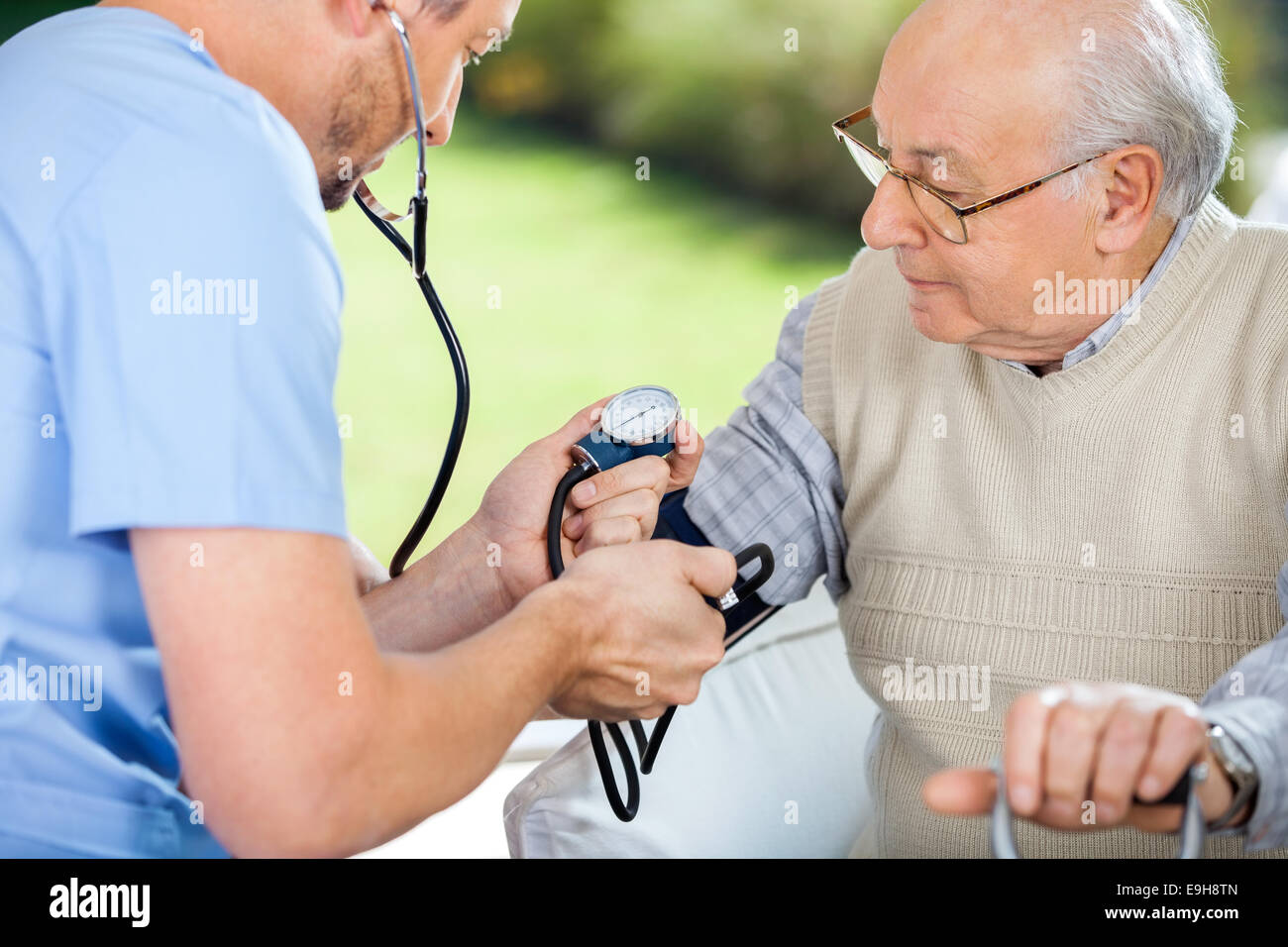 Infermiere controllando la pressione del sangue di uomo senior Foto Stock