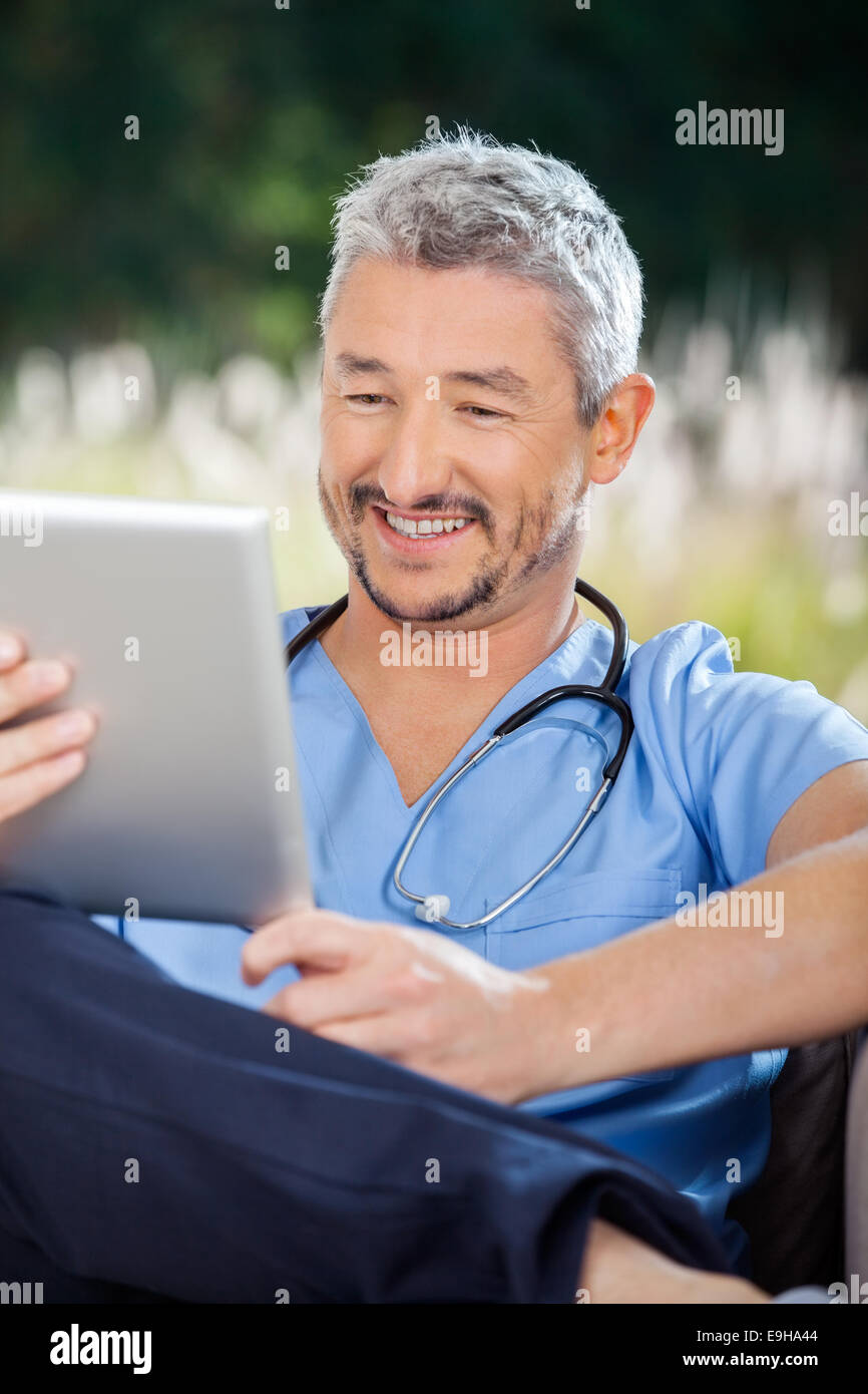 Infermiere sorridente mentre guarda il computer tablet Foto Stock