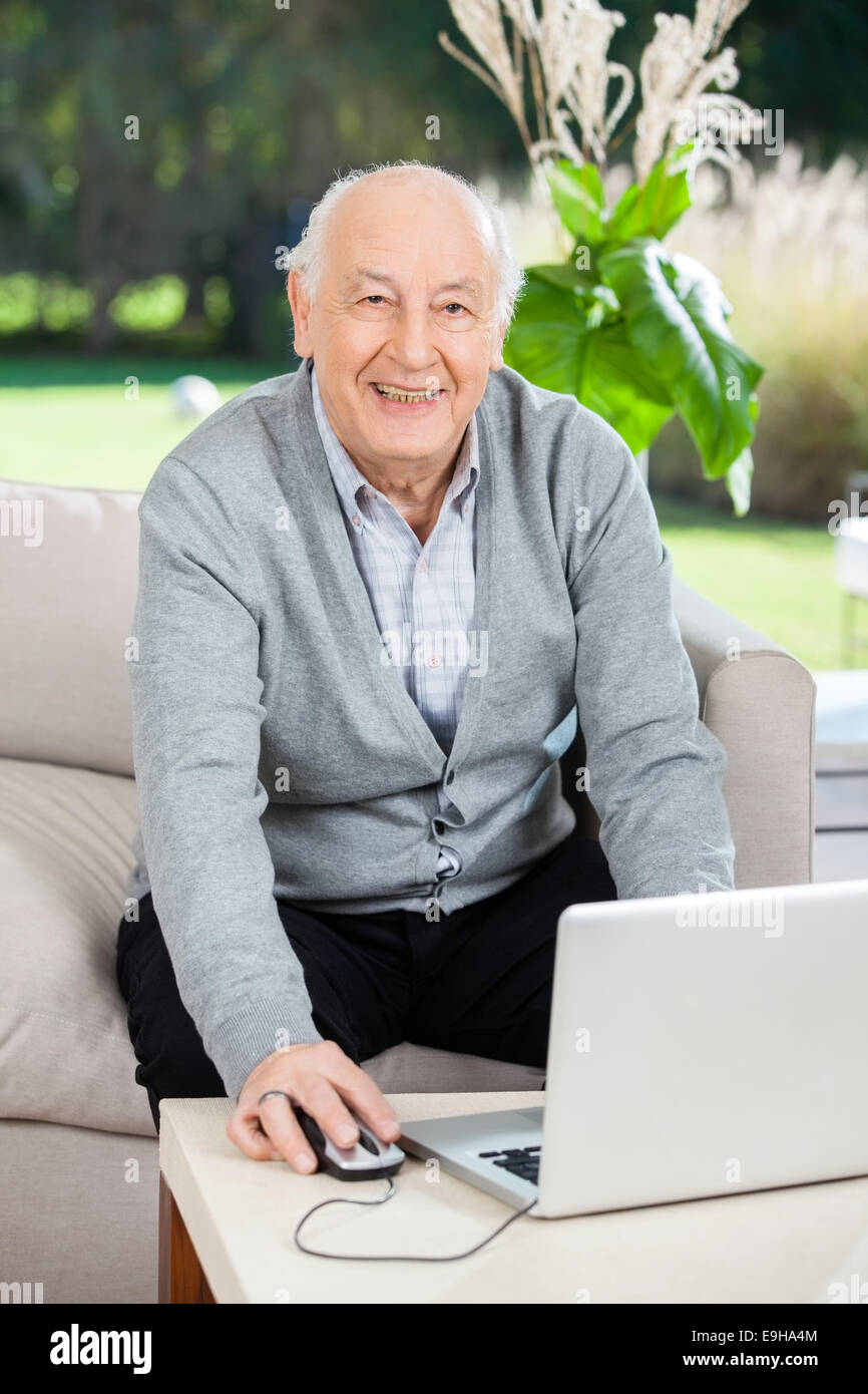 Felice l'uomo senior utilizzando computer portatile presso la casa di cura portico Foto Stock
