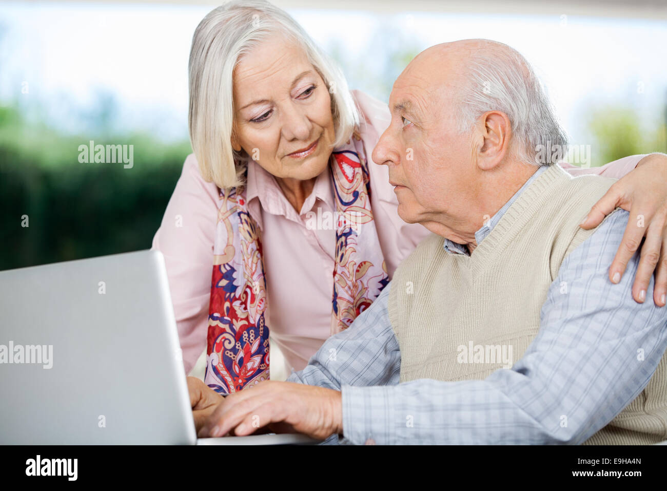Coppia senior che si guarda l'un l'altro mentre si utilizza un notebook Foto Stock