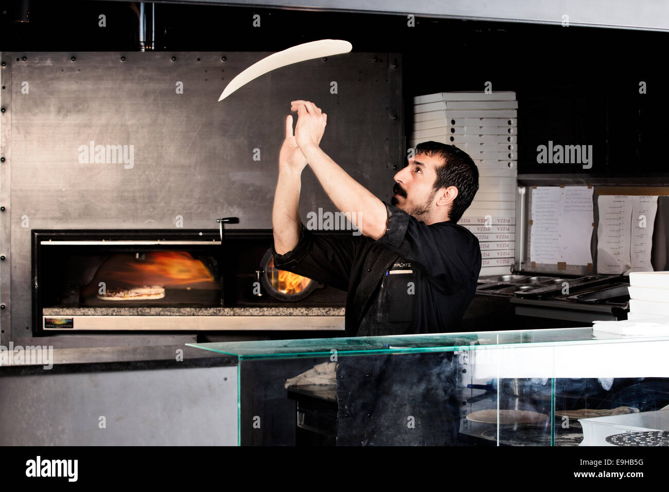 Pizzaiolo preparare la pasta della pizza, pasta della pizza viene gettato  in aria nella parte anteriore del forno per pizze Foto stock - Alamy