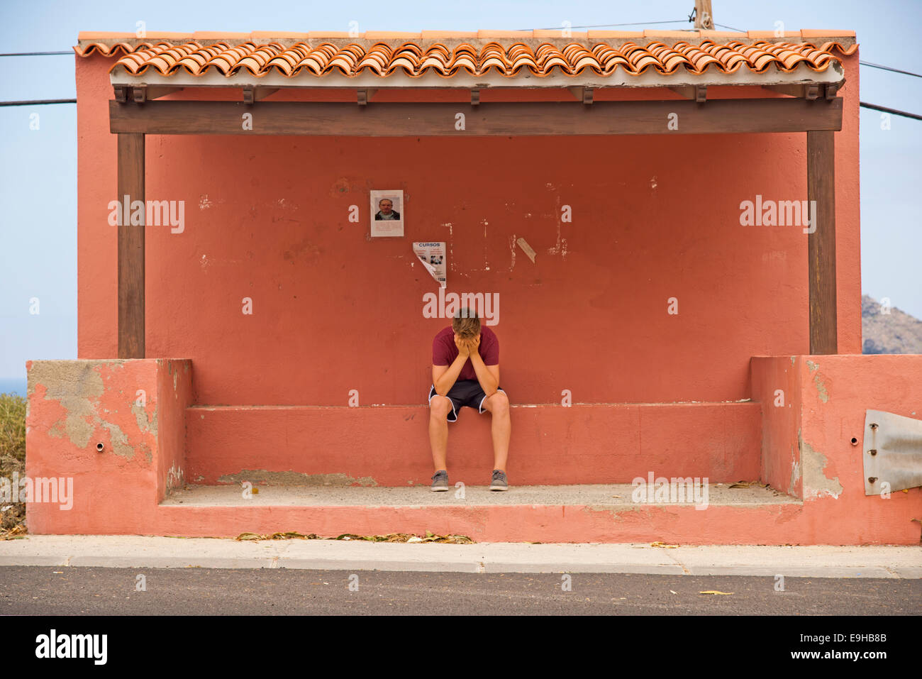 Frustrati boy, 13, in corrispondenza di una fermata bus, Tenerife, Isole Canarie, Spagna Foto Stock