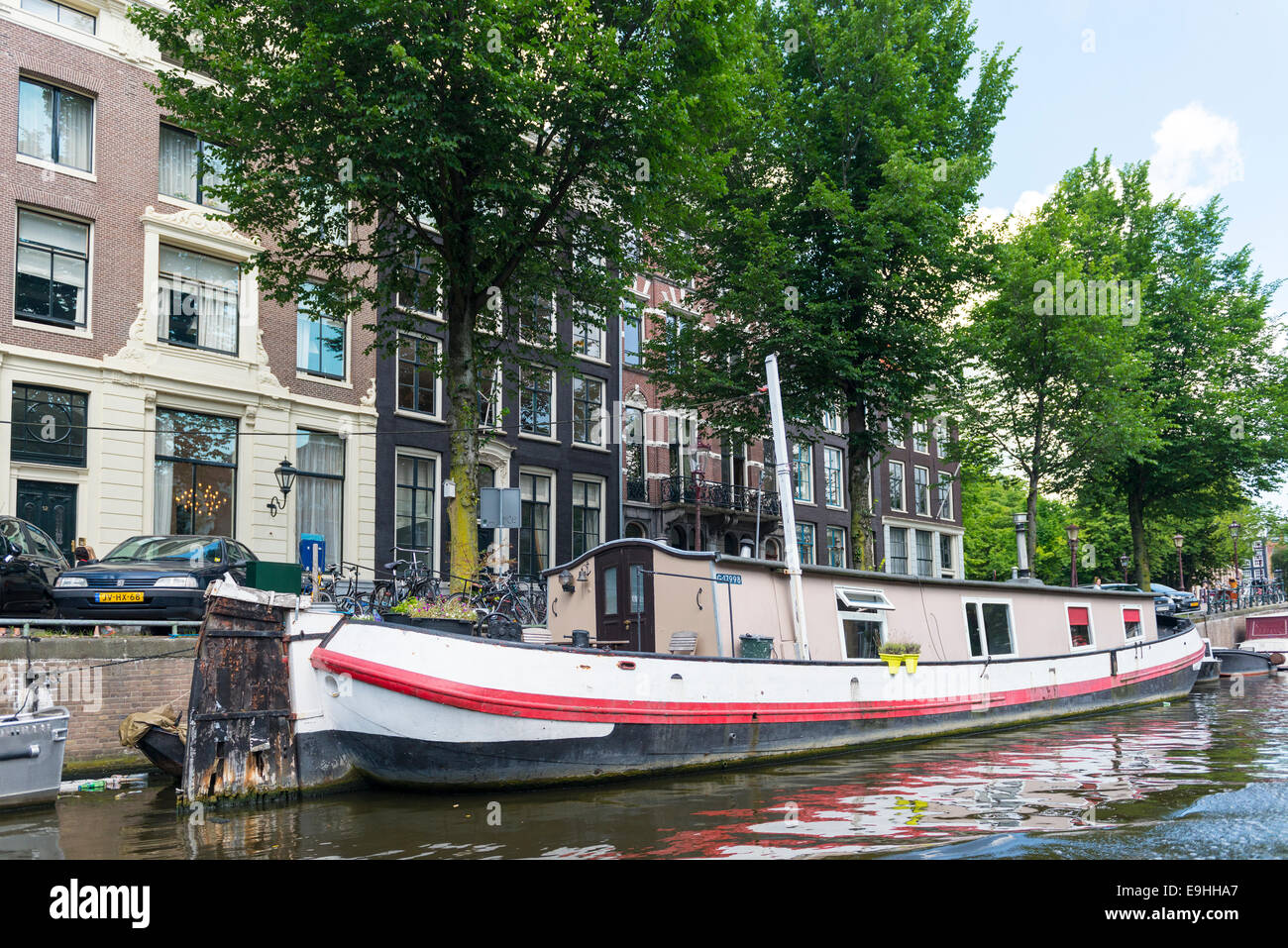 Houseboat presso la banca di un canale con alberi, Amsterdam, Paesi Bassi Foto Stock