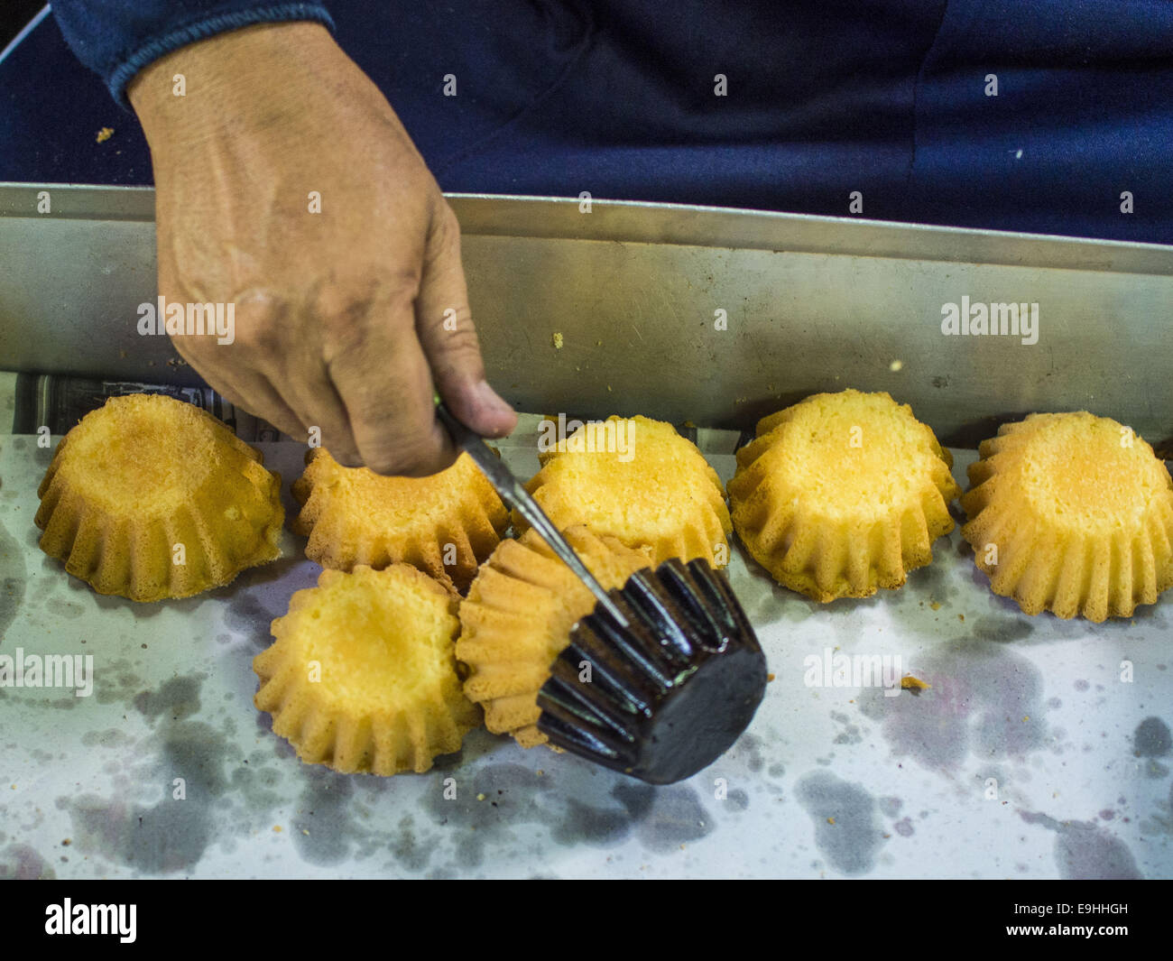 Bangkok, Bangkok, Thailandia. 28 ott 2014. Un lavoratore torte tira fuori del forno al Pajonglak Maneeprasit panificio a Bangkok. I dolci sono chiamati ''Kanom Farang Kudeejeen'' o ''monaco cinese Candy.'' la tradizione della cottura di torte, circa la dimensione di un cupcake o muffin, iniziato nel Siam (ora la Tailandia) nel XVII secolo d.c. quando portoghese sacerdoti cattolico portoghese accompagnato i soldati che hanno assistito il Siamese in le loro guerre con la Birmania. Diverse centinaia di siamesi (tailandese) buddisti convertito al cattolicesimo e iniziato la cottura di torte. Quando l'impero Siamese in Ayutthaya fu saccheggiata dai Foto Stock