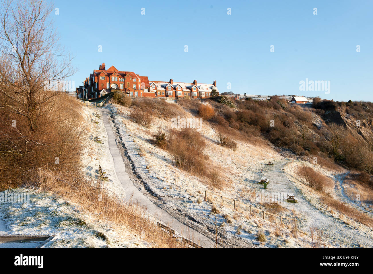 Tetti spolverati di neve e vasi di aragosta impilati a Robin Hood's Bay, Yorkshire, sotto i cieli invernali limpidi e vecchi cavi telegrafici Foto Stock