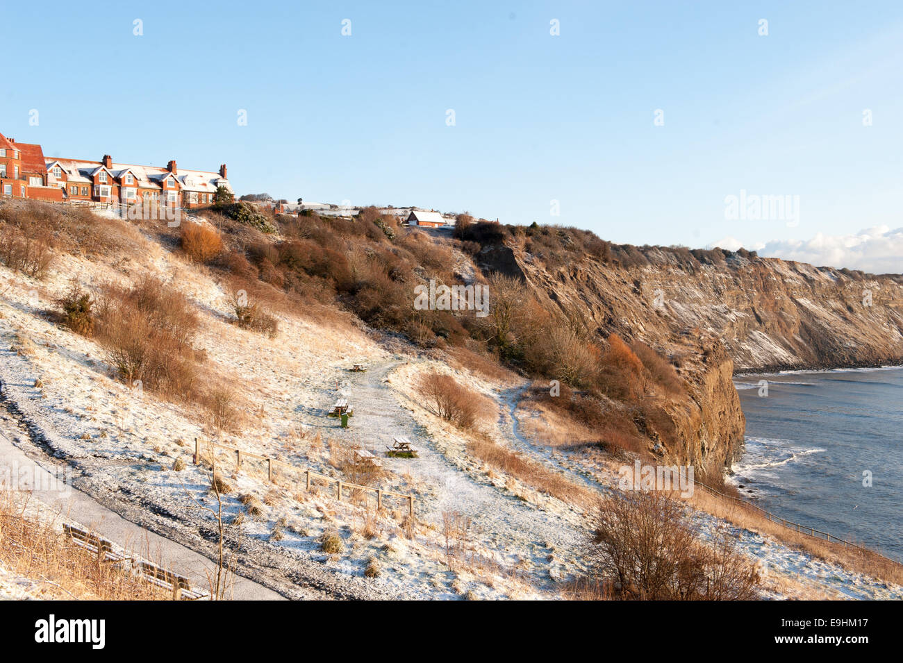 Collina ricoperta di gelo che conduce alle tradizionali case in mattoni rossi nella baia di Robin Hood, illuminate dalla luce solare invernale Foto Stock