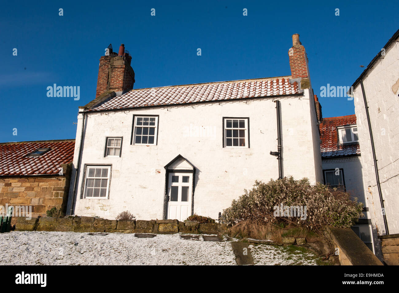 Tetti spolverati di neve e vasi di aragosta impilati a Robin Hood's Bay, Yorkshire, sotto i cieli invernali limpidi e vecchi cavi telegrafici Foto Stock
