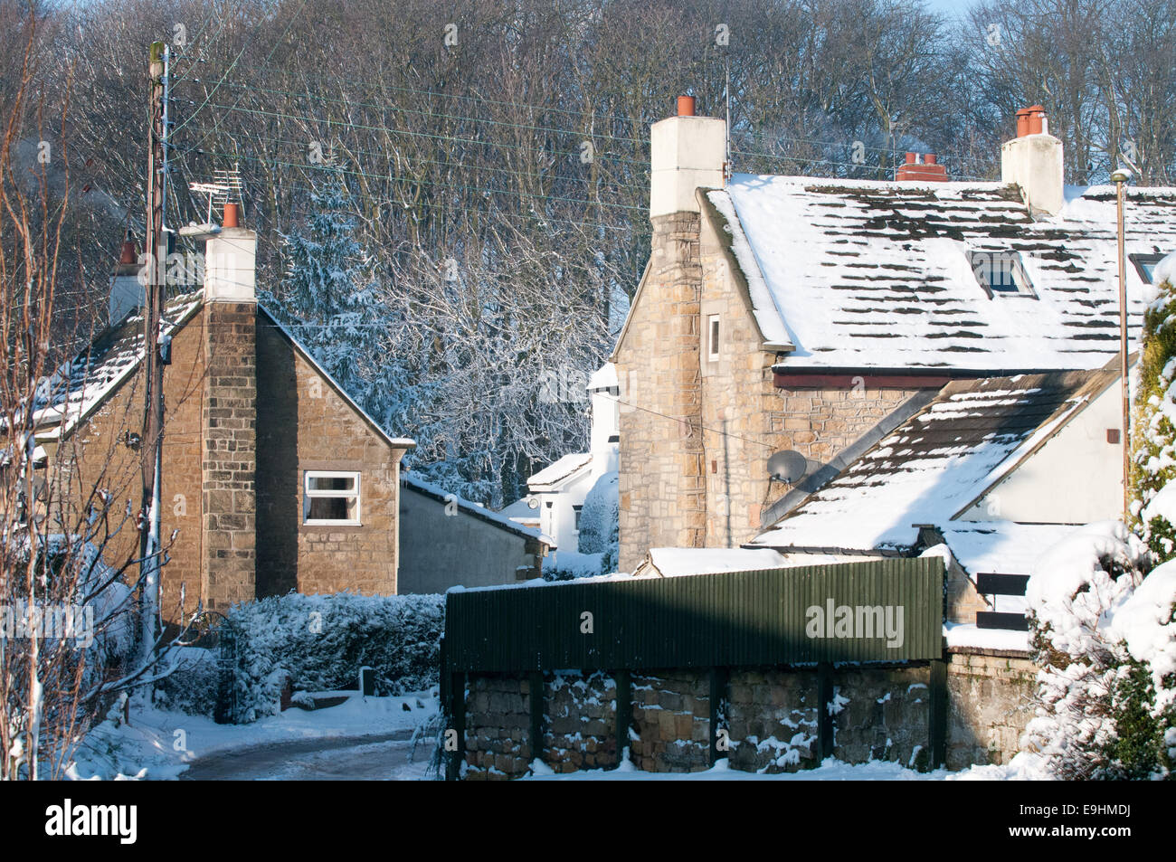 Tetti spolverati di neve e vasi di aragosta impilati a Robin Hood's Bay, Yorkshire, sotto i cieli invernali limpidi e vecchi cavi telegrafici Foto Stock