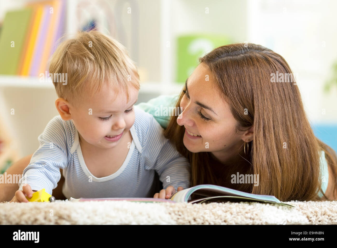 Madre la lettura di un libro per bambini a casa Foto Stock
