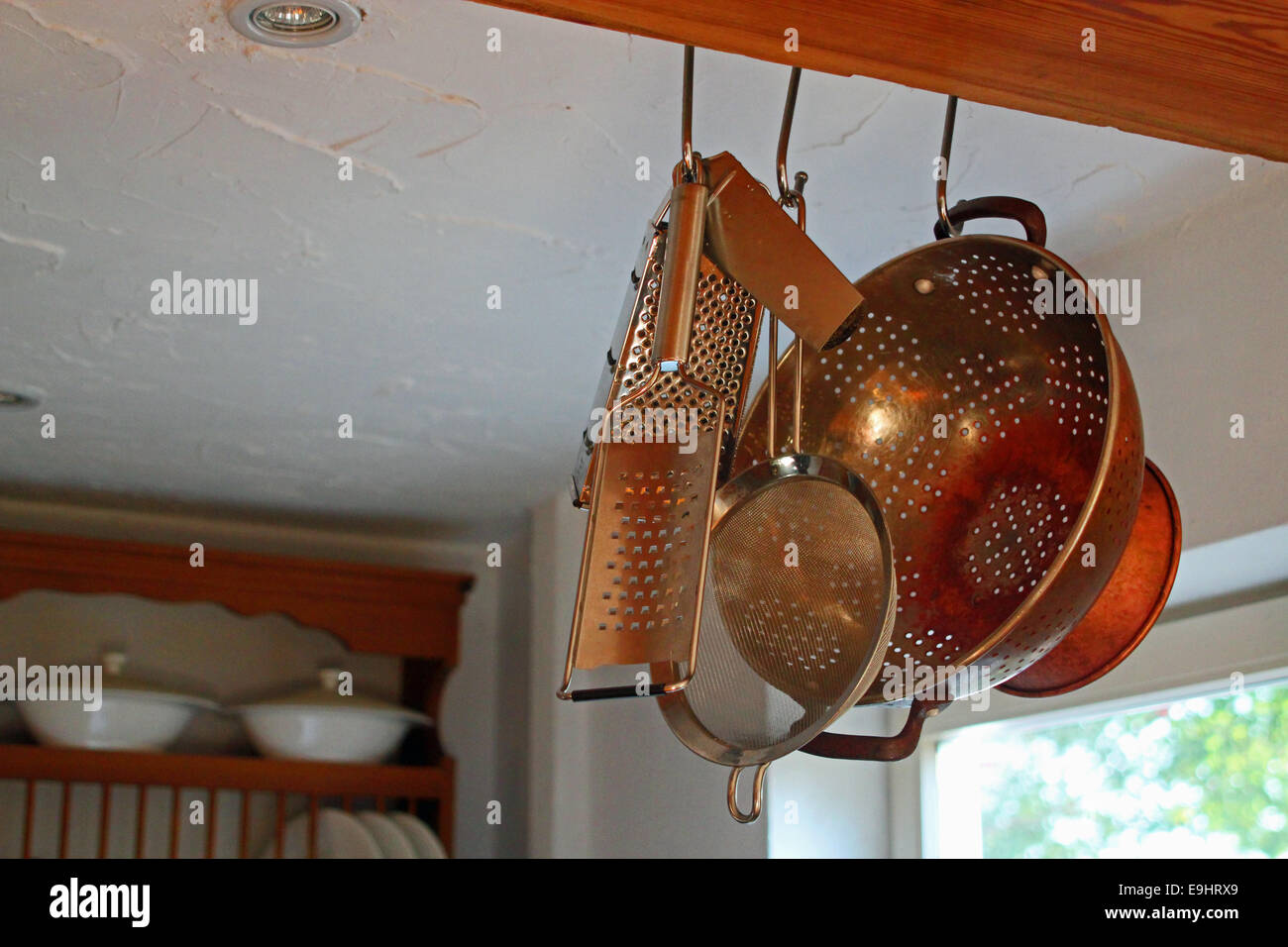 Cucina di paese con close-up di utensili da cucina pende da una trave con piastra in rack lo sfondo Foto Stock