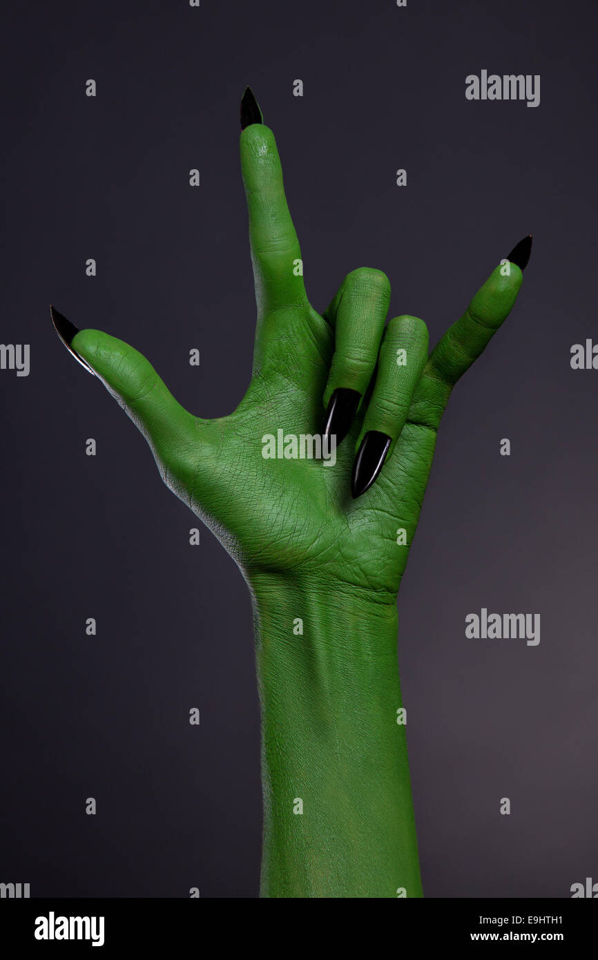 Mano verde con unghie nere che mostra heavy metal gesto, studio shot su sfondo nero Foto Stock
