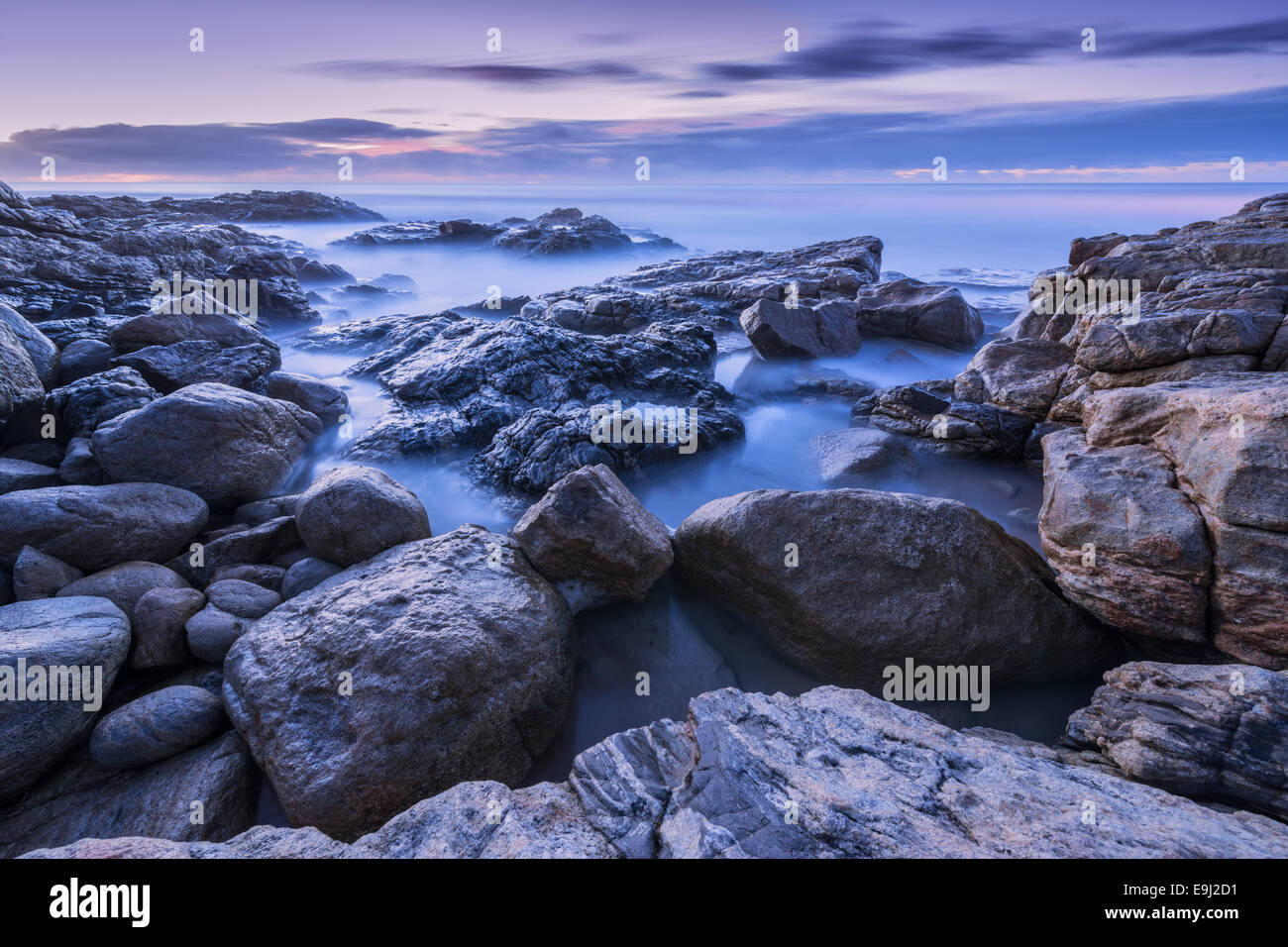 Pre-alba fotografia di misty onde che si infrangono sulle rocce dalla costa sud in Sud Africa Foto Stock