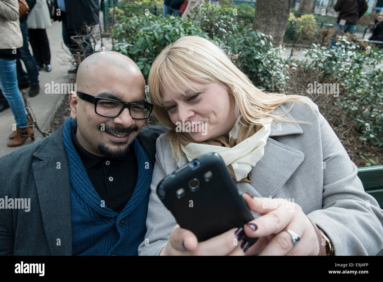 Un vero e autentico giovane seduto su una panchina di Parigi e prendere un selfie su uno smart phone mentre cercano felice Foto Stock