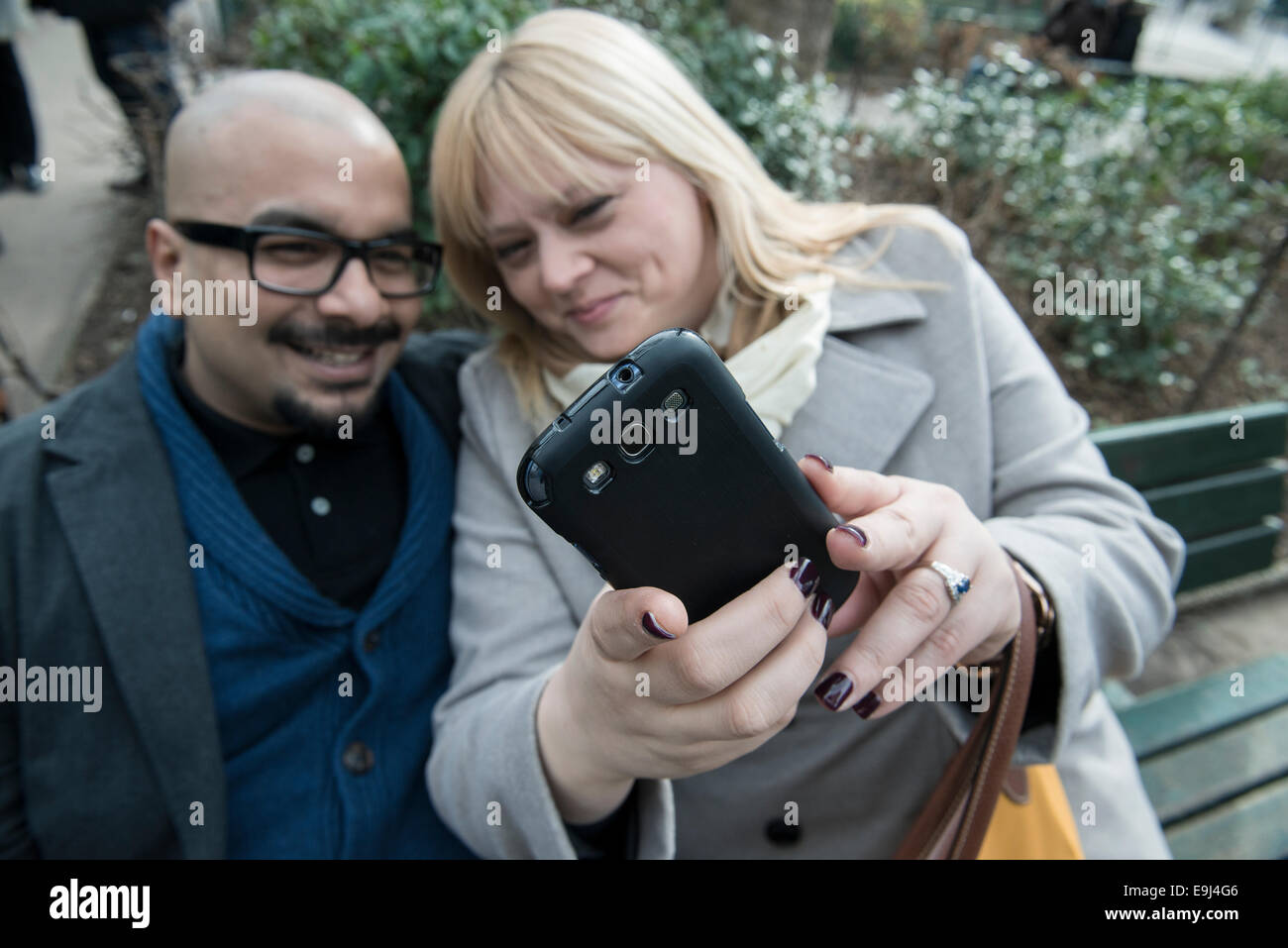 Un vero e autentico giovane seduto su una panchina di Parigi e prendere un selfie su uno smart phone mentre cercano felice Foto Stock