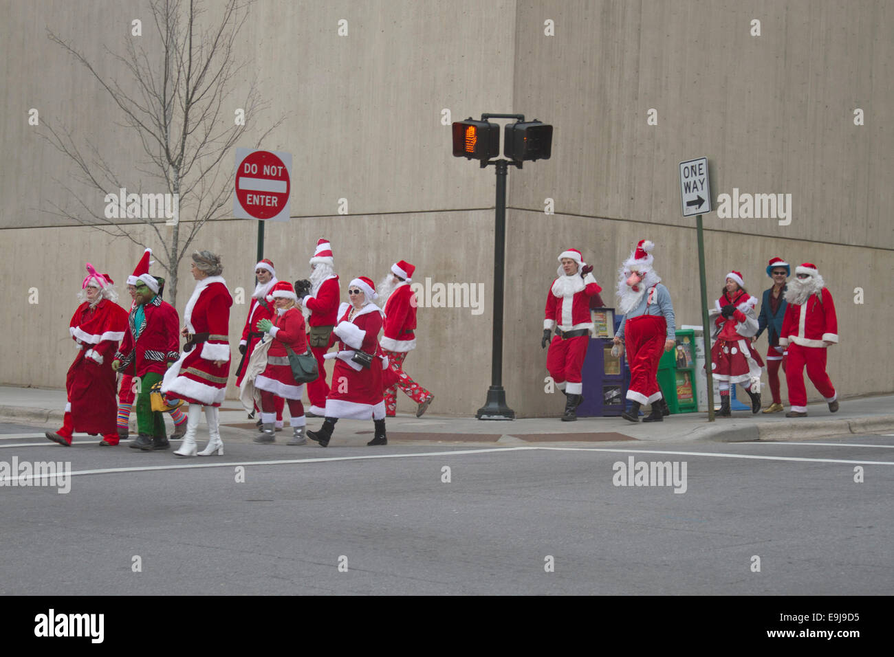 Un pacco di Babbo Natale, MRS. Le clausole e gli elfi attraversare una strada nel centro di Asheville intorno a Natale durante l'evento santacon Foto Stock