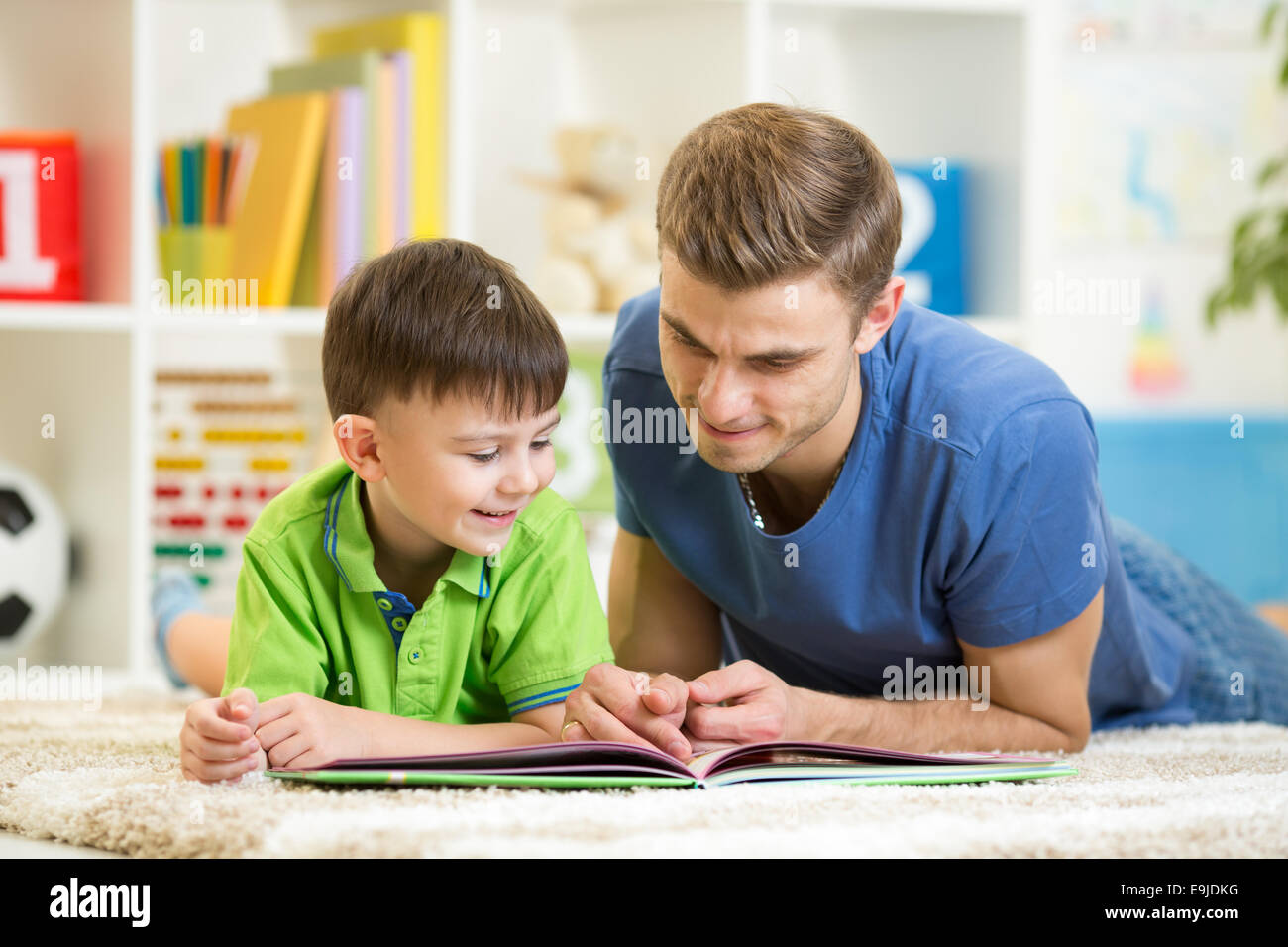 Bambino ragazzo e papà leggere un libro sul pavimento a casa Foto Stock