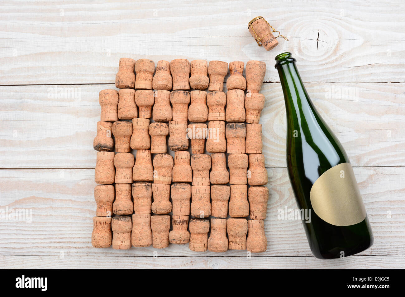 Alta angolazione di un vuoto bottiglia di champagne con etichetta vuota e tappi in sughero. Primo piano su un rustico di legno bianco tavola. Formato orizzontale Foto Stock