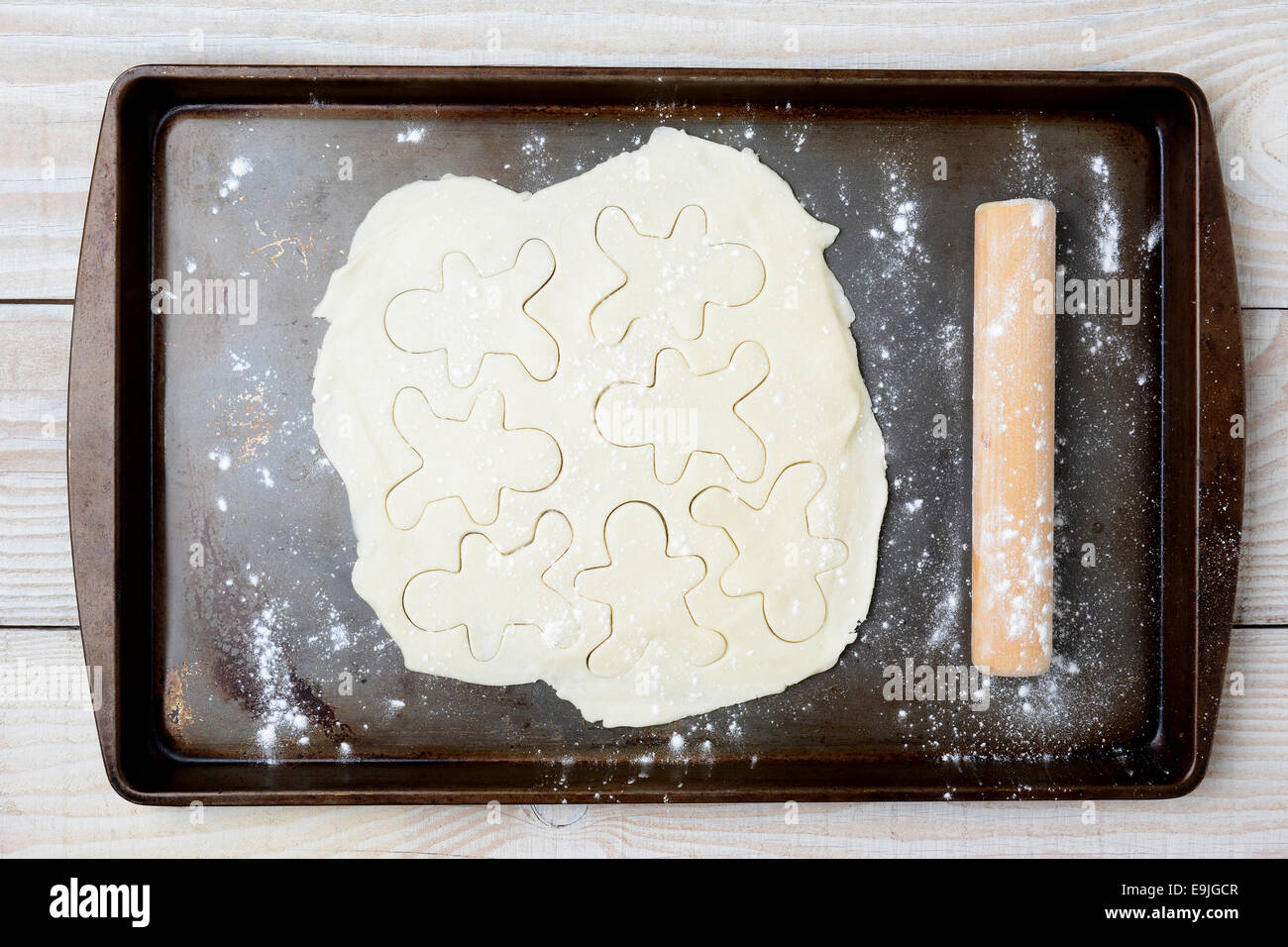 Alta angolazione della pasta biscotto con pan di zenzero uomini forme. La pasta è su un vecchio usato la teglia con la farina e un rotolo di legno Foto Stock