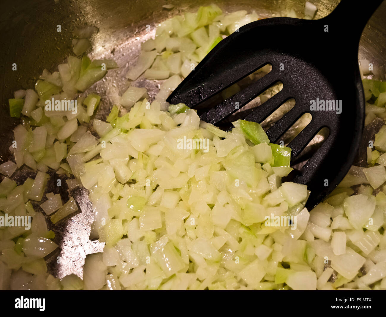 Sautéing cipolle in una padella. La cottura di cipolle in una pentola con una spatola. Soffriggere le cipolle sul fornello. Foto Stock