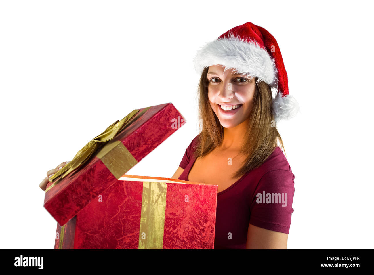 Bella bruna in santa hat apre un regalo sorridente in telecamera Foto Stock