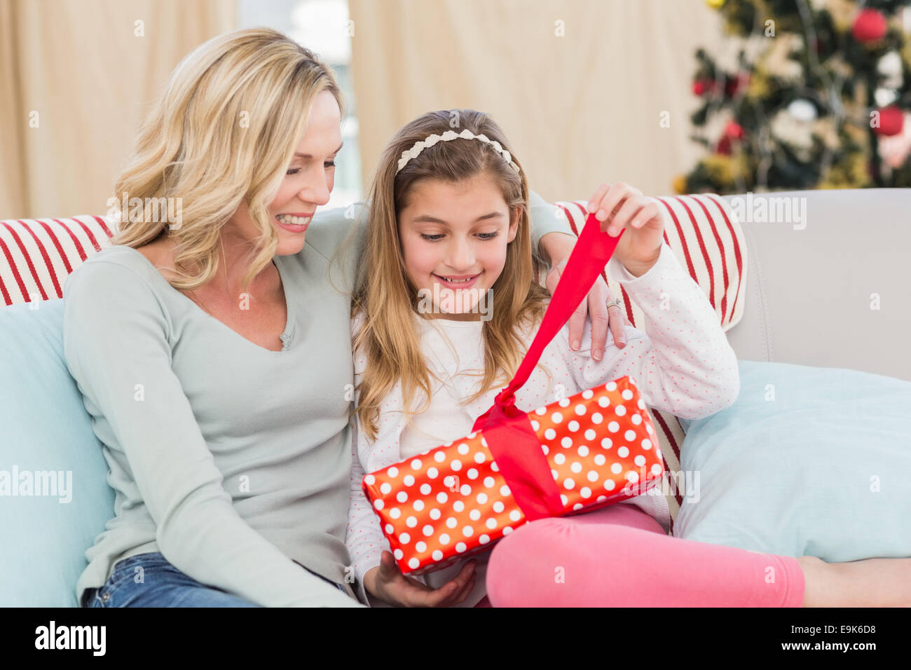 Incantevole piccola ragazza seduta sul lettino dono di apertura con la mamma Foto Stock