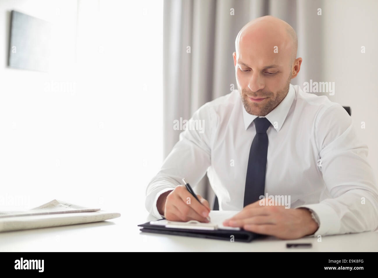 Adulto medio imprenditore iscritto negli appunti in home office Foto Stock