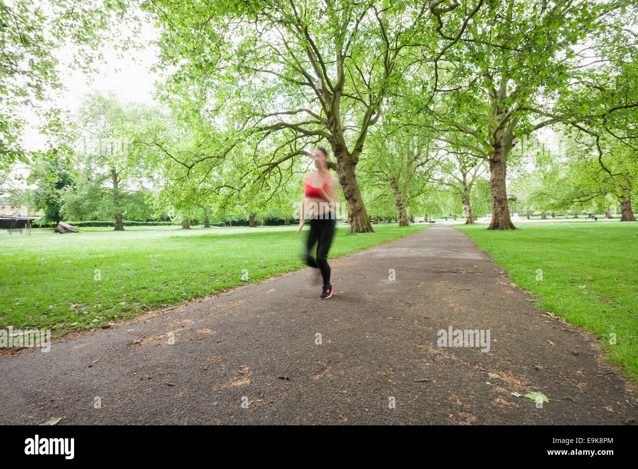 Moto offuscata da donna a fare jogging nel parco Foto Stock