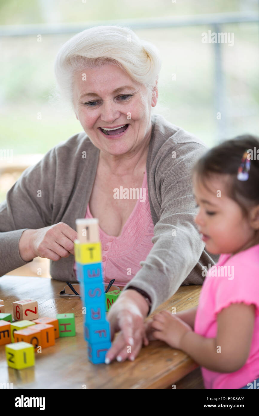 Felice la nonna e la nipote giocare con alfabeto di blocchi in casa Foto Stock