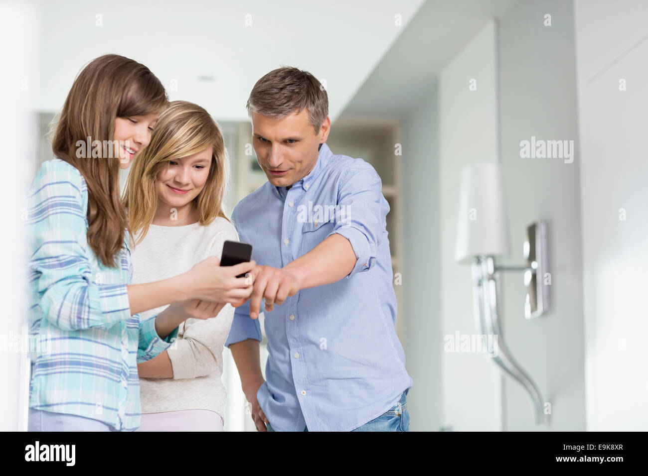 Uomo di mezza età con le figlie utilizzando smart phone a casa Foto Stock