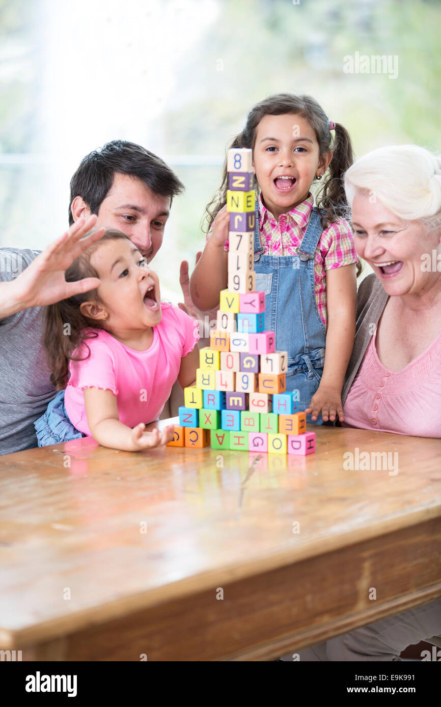 Felice multi generazione famiglia con disposti blocchi di costruzione a tavola in casa Foto Stock
