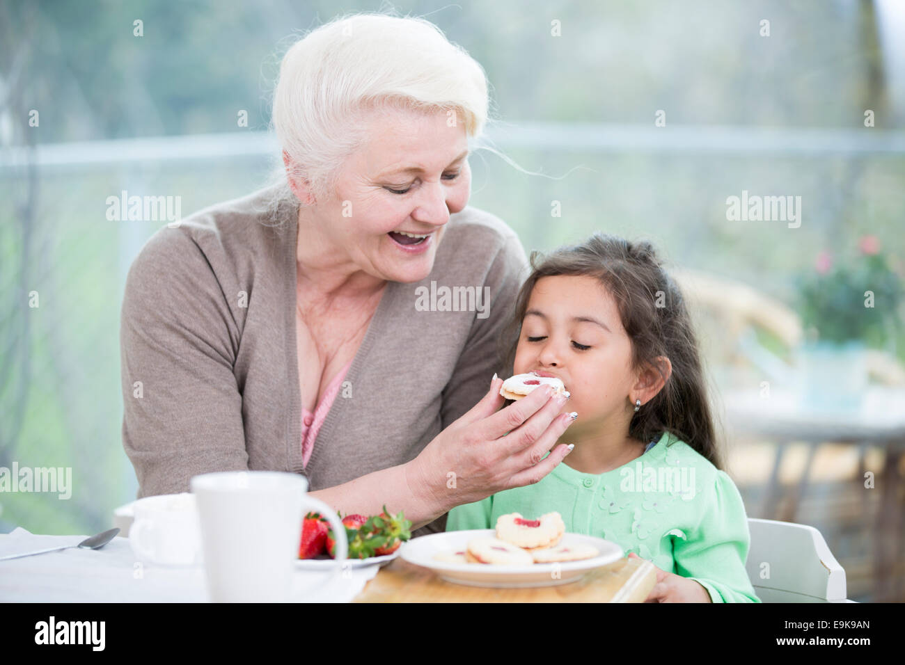 Felice senior alimentazione donna cookie al nipote a casa Foto Stock