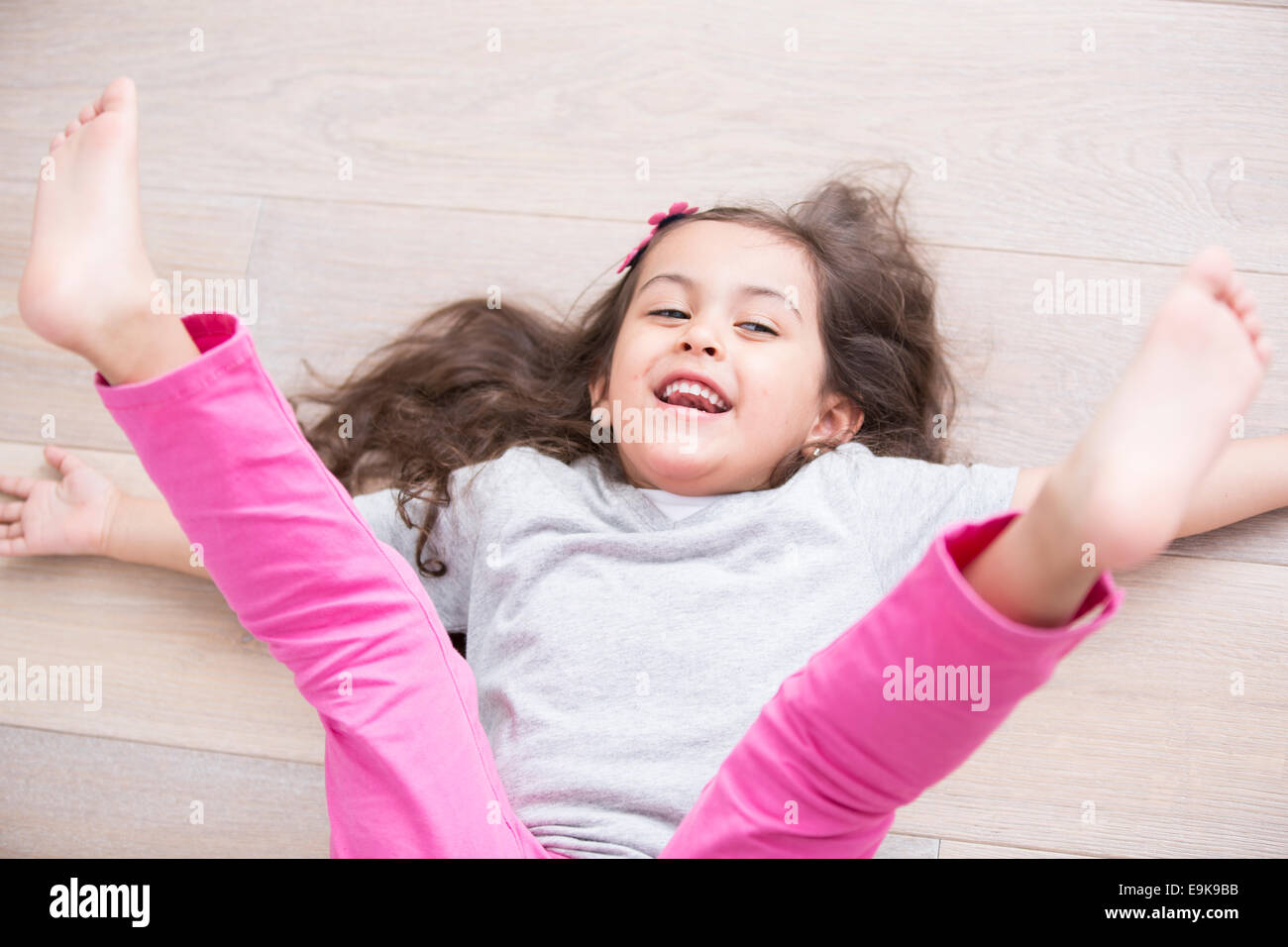 Angolo di alta vista di giocoso ragazza distesa sul pavimento con le gambe sollevate a casa Foto Stock