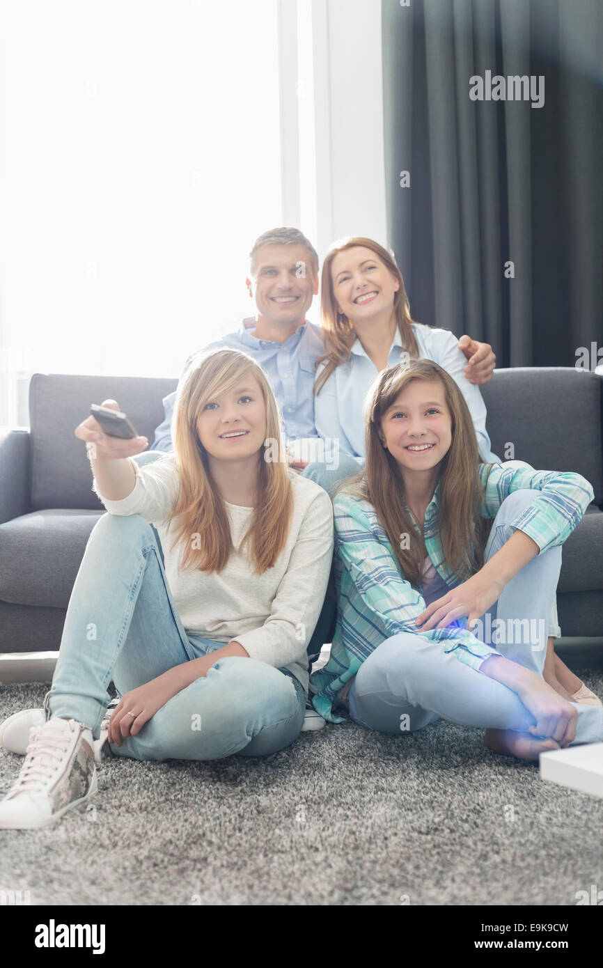 La famiglia felice di quattro guardando la TV insieme a casa Foto Stock